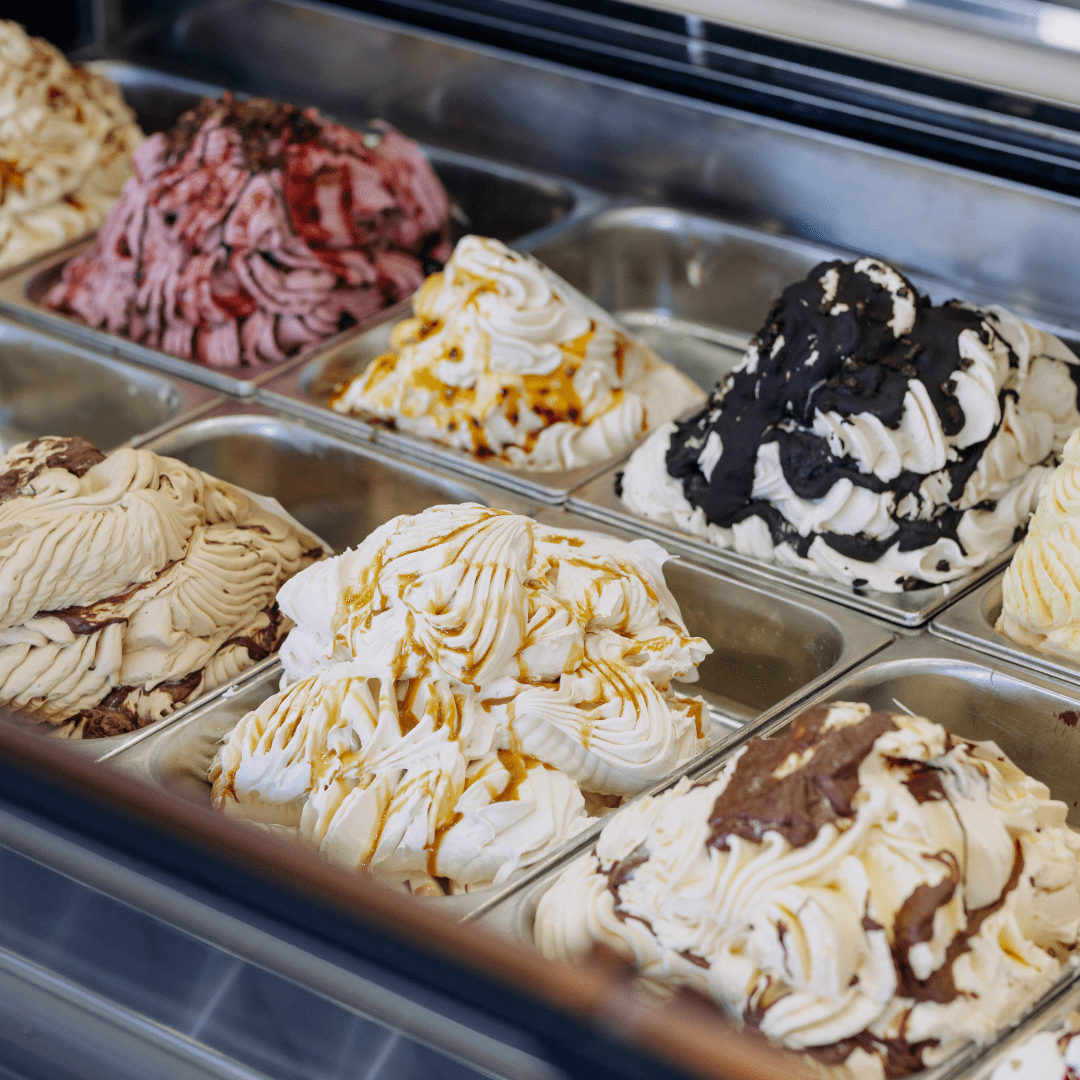 Diverse smaken ambachtelijk schepijs, rijkelijk afgewerkt met siropen en toppings.